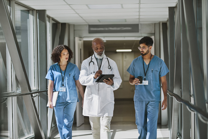 Physicians walking down hallway, conversing about a patient